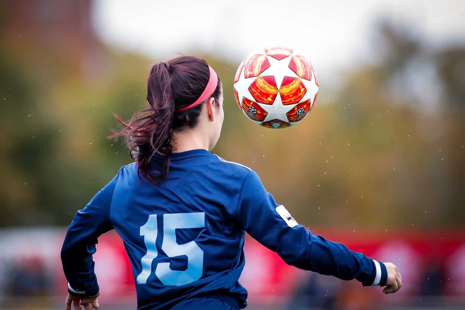 Young women with eyes focused on the soccer ball while controlling it during a girl football match.